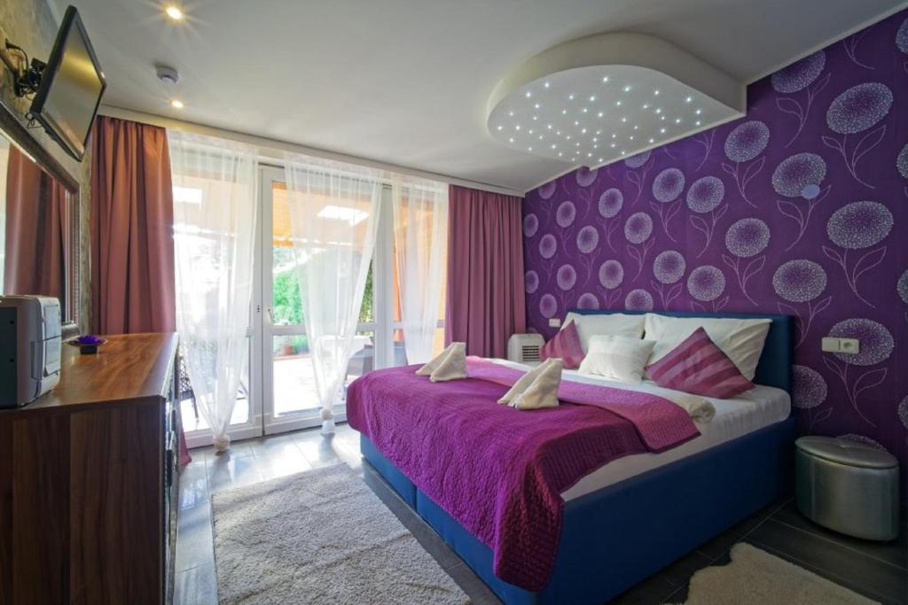 Dormitorio púrpura con cama con pared púrpura en Penzion Janka en Brno