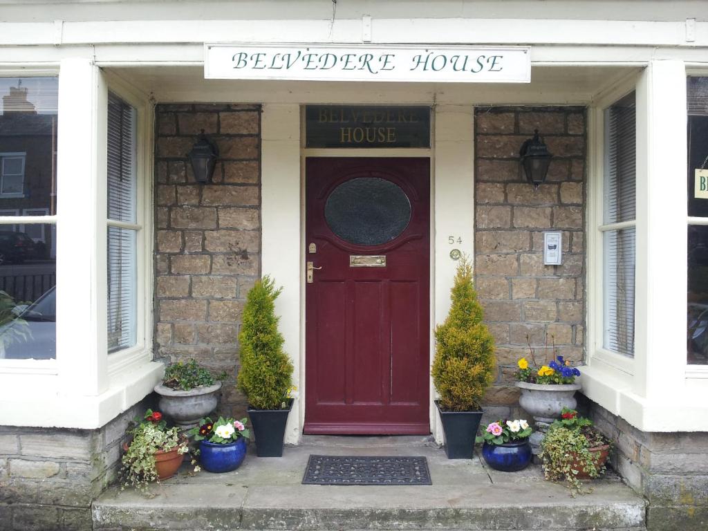 a red front door of a house with potted plants at Belvedere House in Middleton in Teesdale