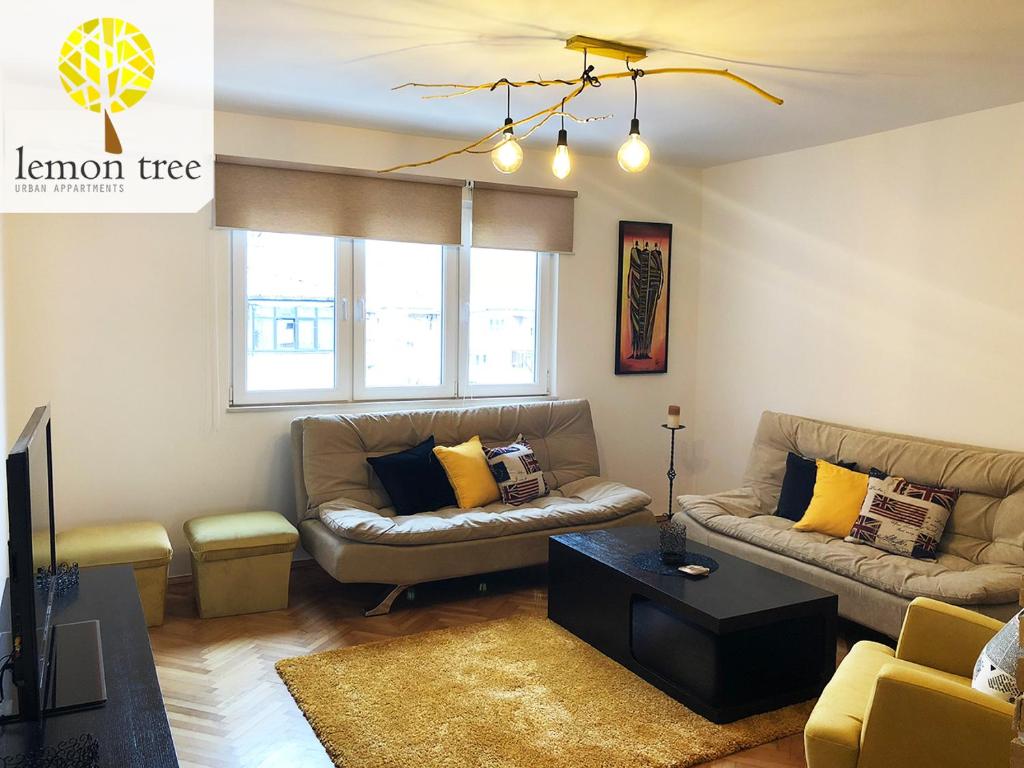 - un salon avec un canapé et une table dans l'établissement Lemon Tree Apartment, à Pristina