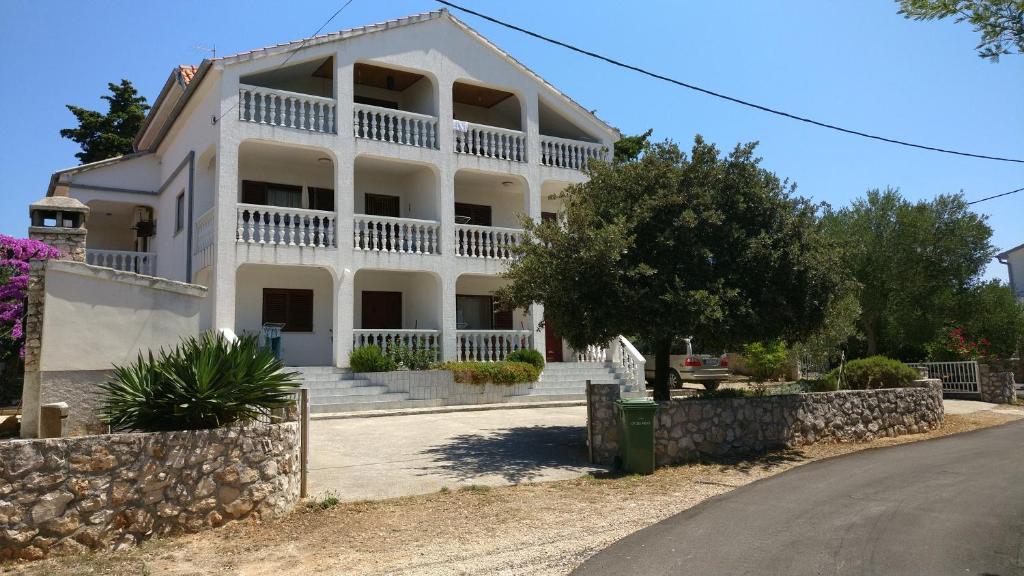 a large white house with a stone wall at Apartments Antolkovic in Ugljan