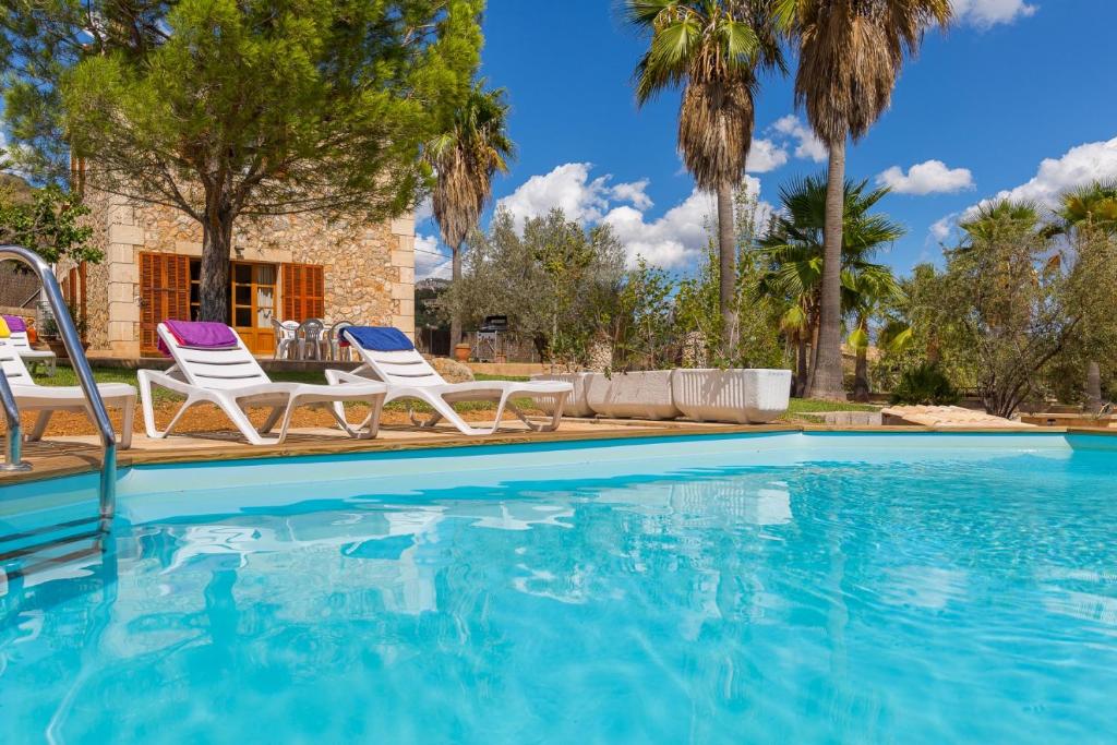 a swimming pool with two chairs and a house at Banyols in Alaró