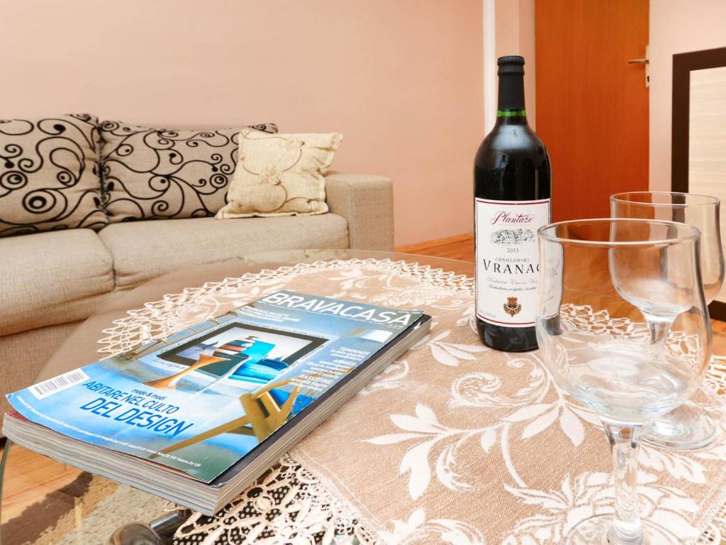 a bottle of wine and a book on a table at Apartments Ivo Bozinovic in Tivat