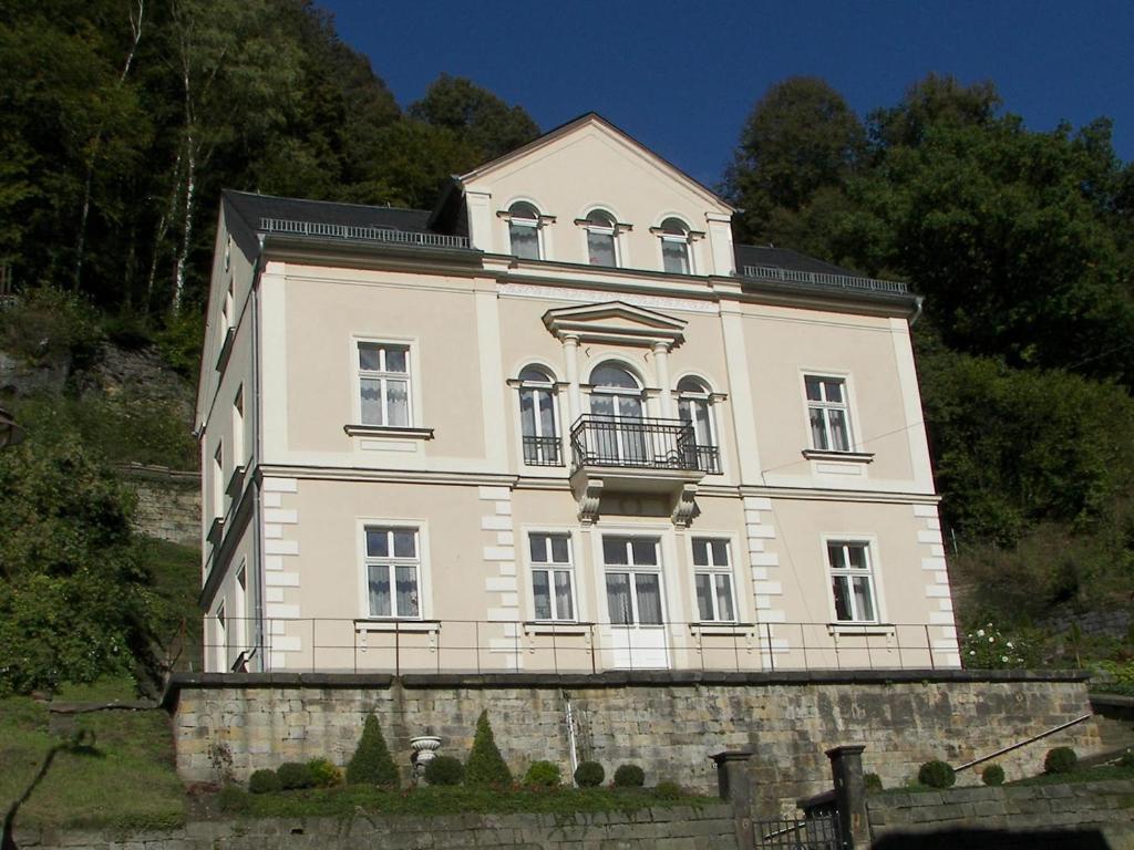 une grande maison blanche au sommet d'une colline dans l'établissement Ferienwohnungen Wilhelm, à Bad Schandau