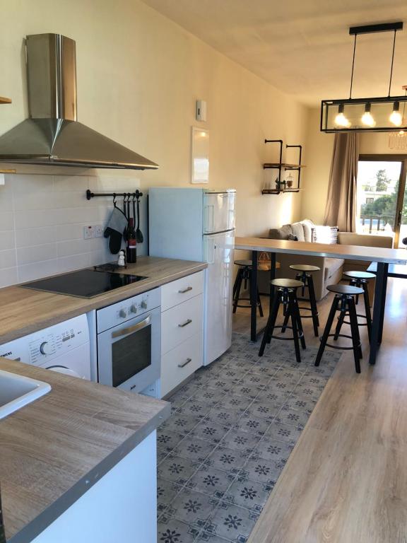 una cocina con electrodomésticos blancos y una mesa con taburetes en Evitas House en Pafos