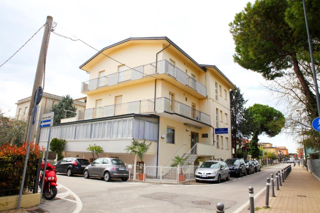 un edificio amarillo con coches estacionados frente a él en Hotel Lagomaggio en Rímini