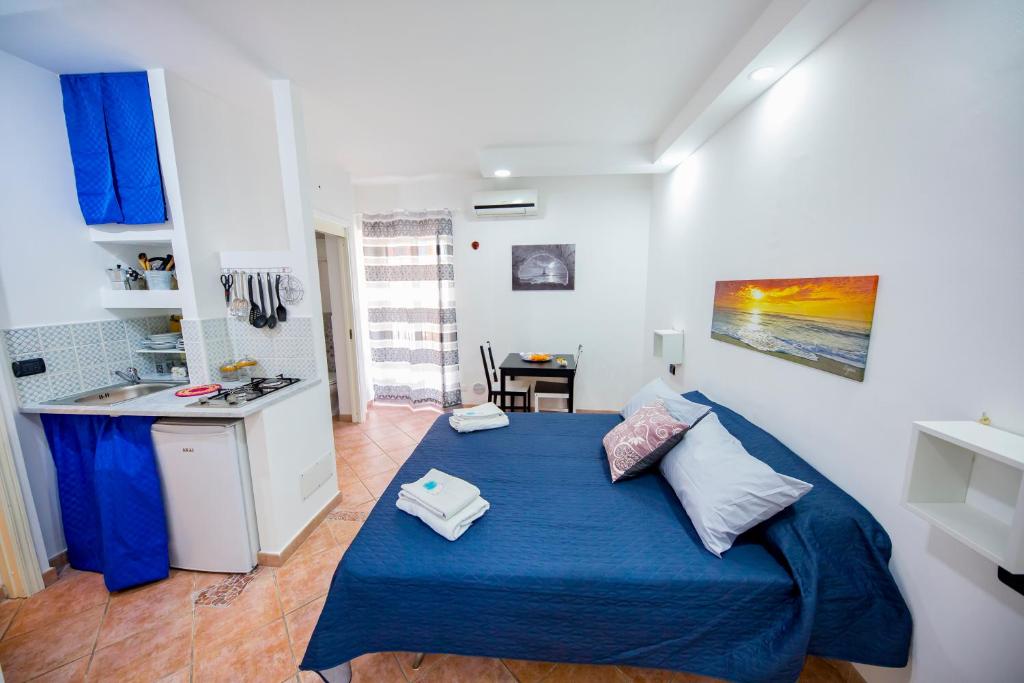1 dormitorio con 1 cama azul y cocina en Casa Rubino, en Cefalú