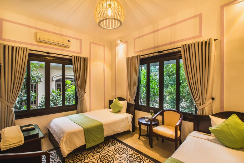 a hotel room with two beds and a chair at Thien Phu Hotel in Hue