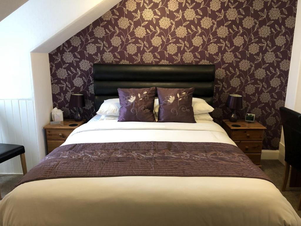 een slaapkamer met een groot bed met paarse kussens bij Rosebank Guest House in Perth
