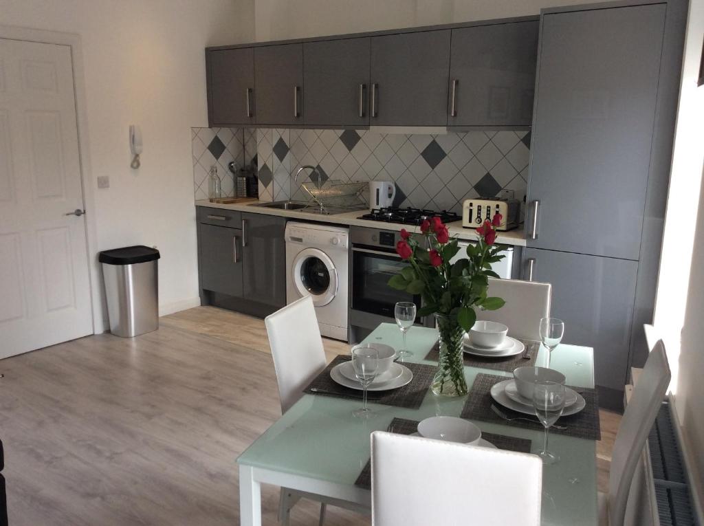 a kitchen with a table with a vase of flowers on it at Rooftop Apartments in Belfast