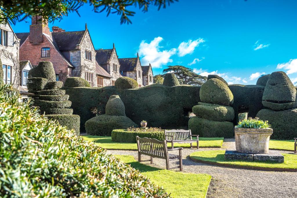 un parco con panchine, alberi e case di The Billesley Manor Hotel a Stratford-upon-Avon