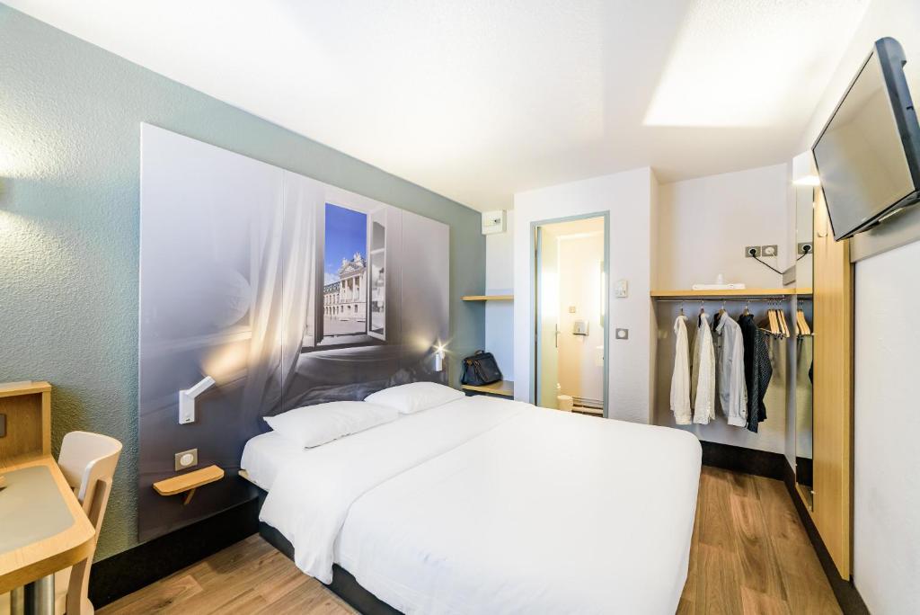 a bedroom with a large white bed and a closet at B&B HOTEL Dijon Marsannay in Dijon