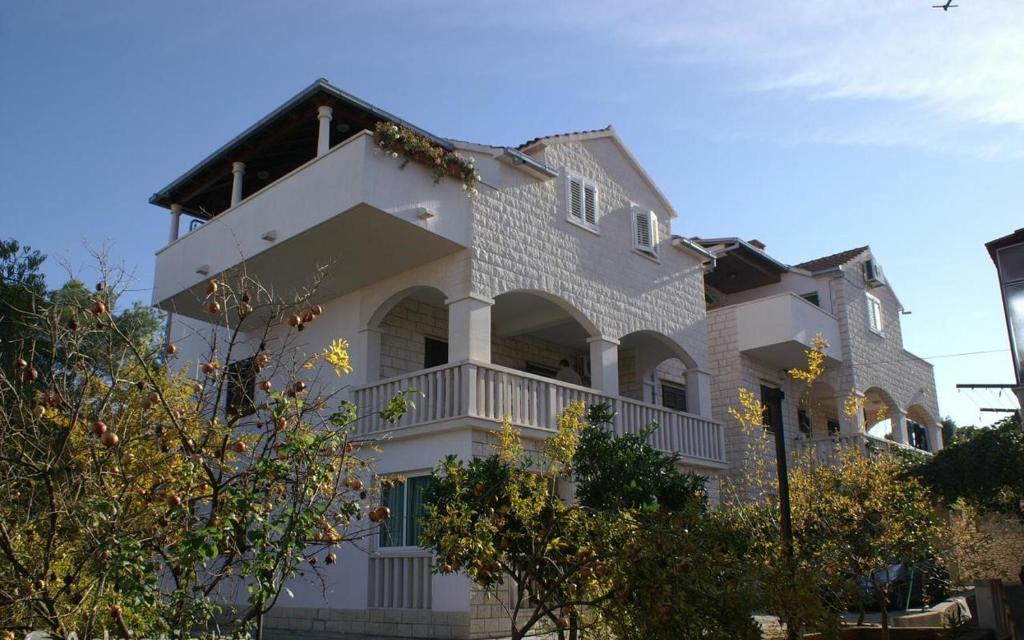 uma grande casa branca com uma varanda em Apartmani Marjana em Supetar