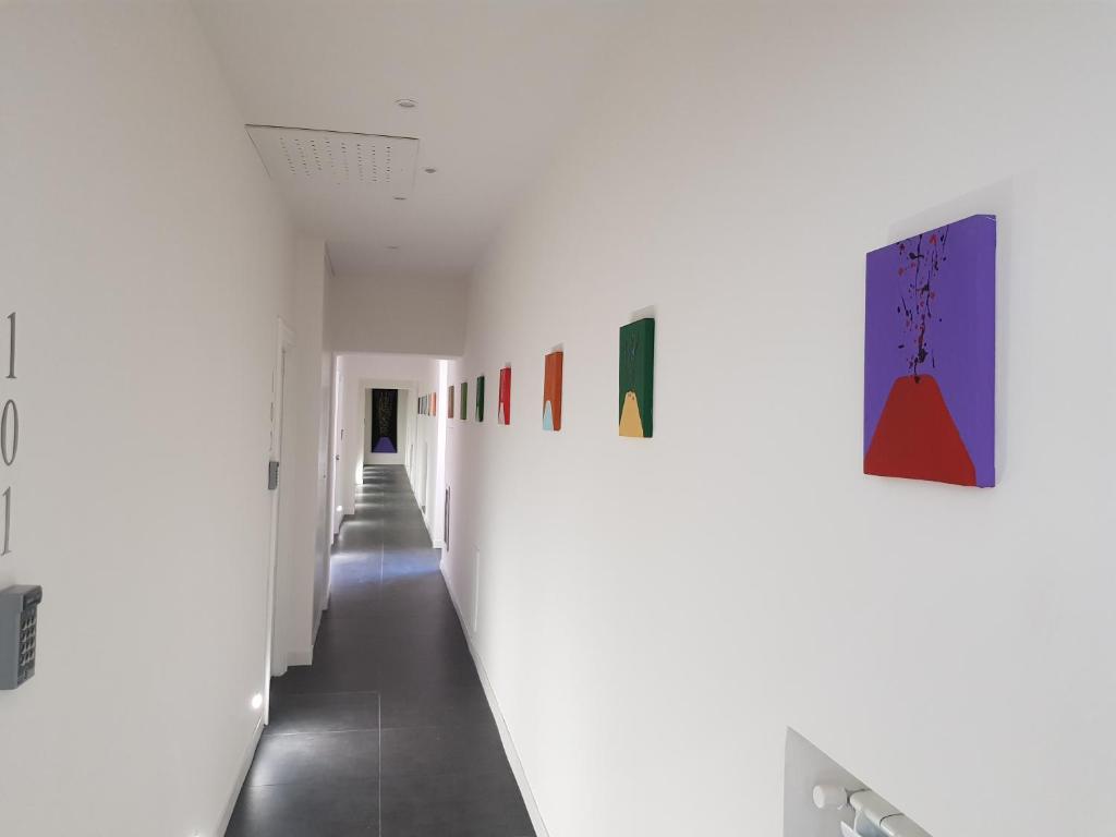 a corridor in a white room with paintings on the walls at Art Street Hotel in Naples