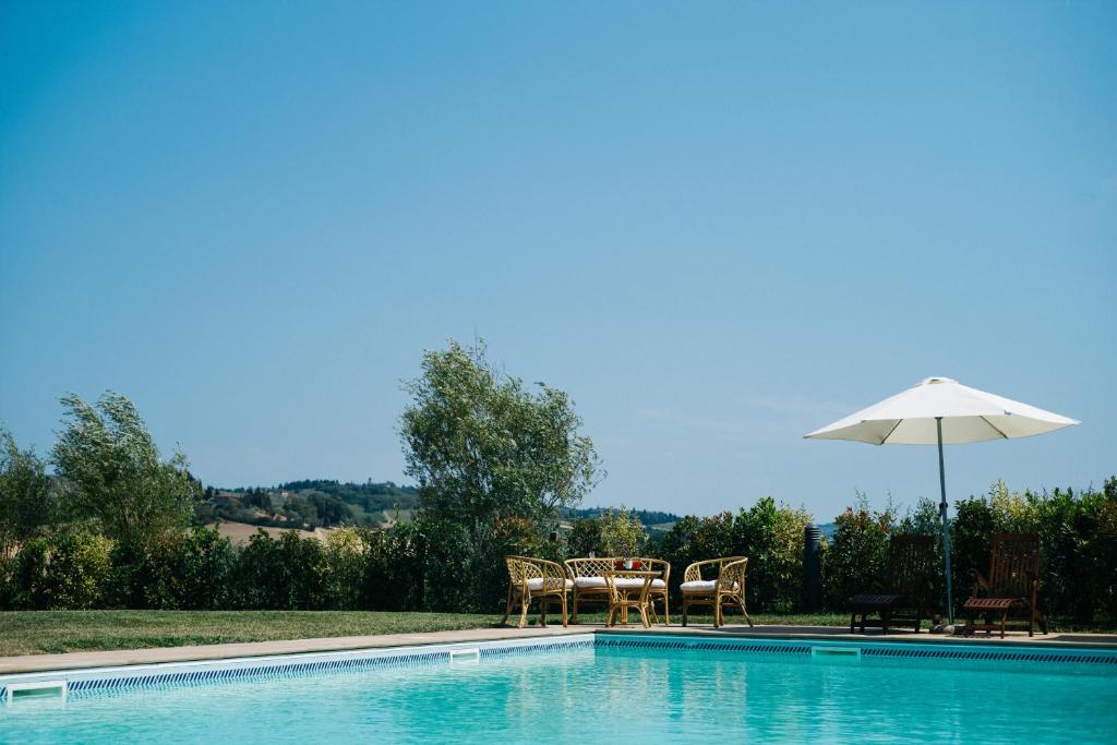 uma piscina com uma mesa e um guarda-sol em Gatto Bianco Tizzauli em Montespertoli