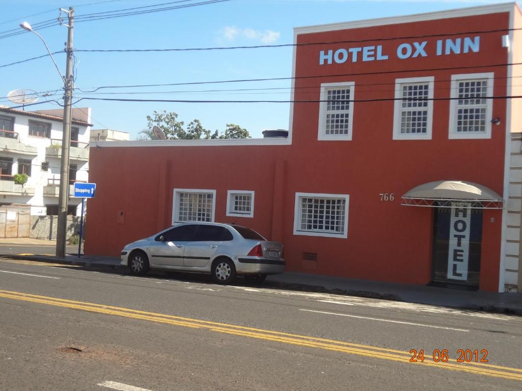 a car parked in front of a red building at Hotel Ox Inn in Uberaba