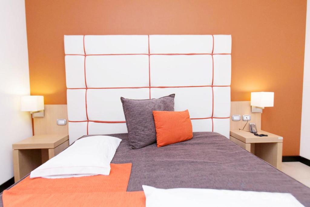 a bedroom with a large bed with an orange wall at Hotel Al Ritrovo in Castelluzzo