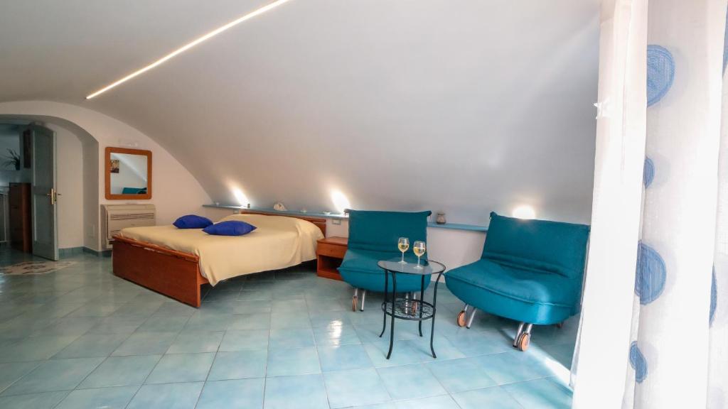 a bedroom with a bed and two blue chairs at La Mostra Boutique Apartment in Maiori