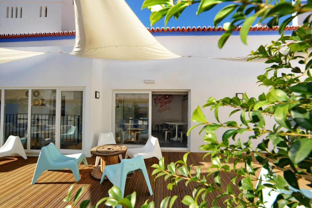 a patio with white chairs and a table and a building at Son of a Beach Hostel in Albufeira
