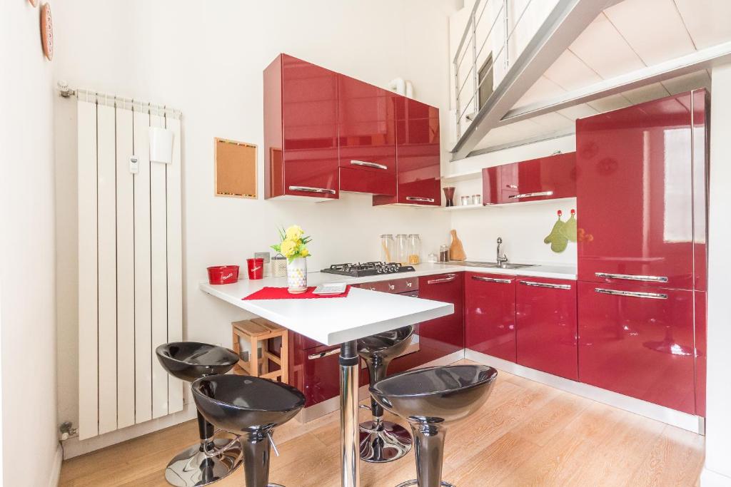 una cucina con armadi rossi e piano di lavoro bianco di Alessia's Flat- Porta Romana M3 a Milano