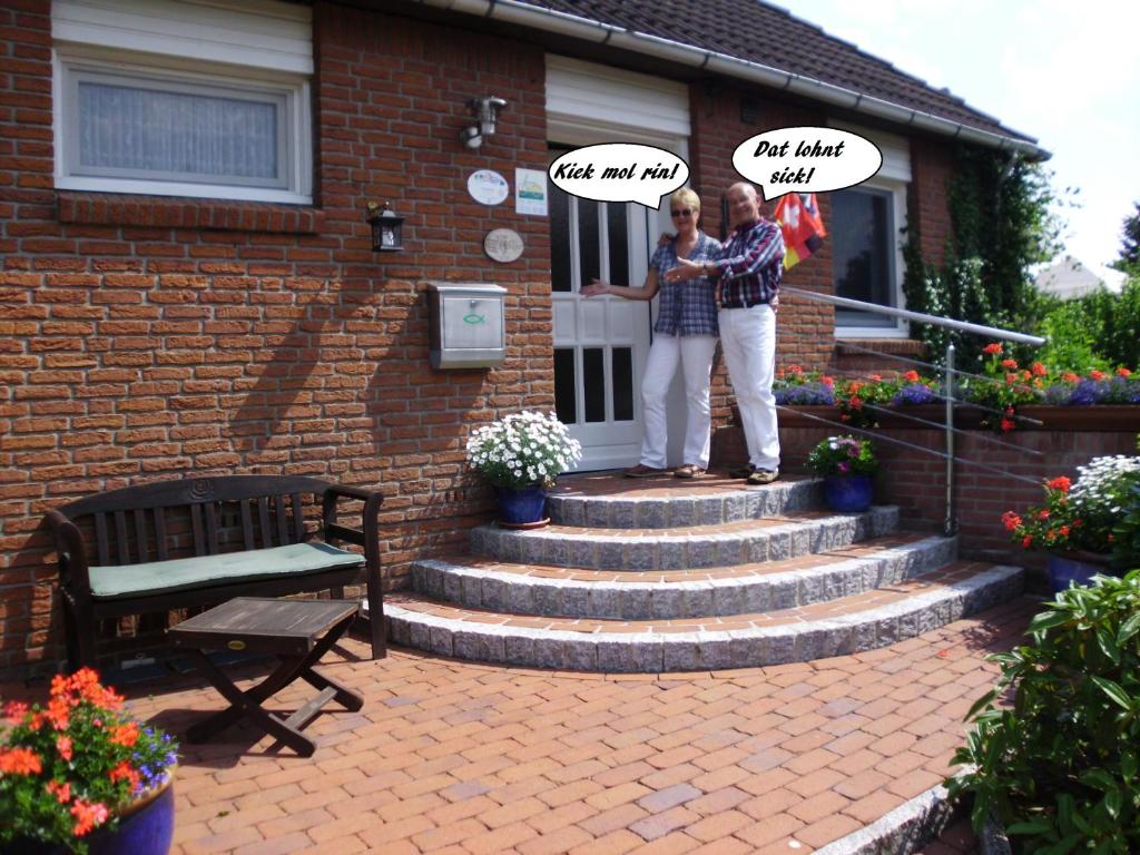 two people standing in front of a house at Gaestehaus Kiekmolrin in Gnarrenburg