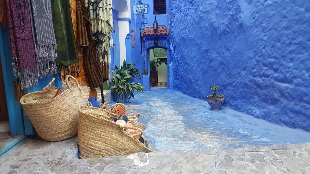 un callejón azul con cestas en el lateral de un edificio en Dar Antonio, en Chefchaouen