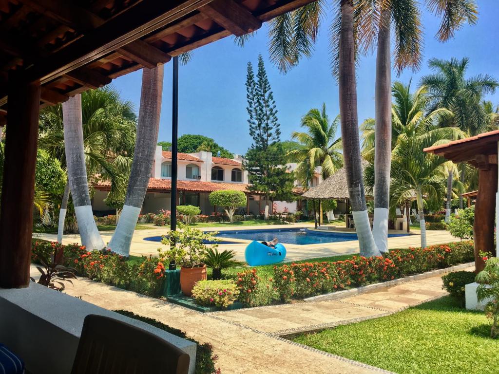 a resort with a swimming pool and palm trees at Casa Romantica De Playa in Ixtapa