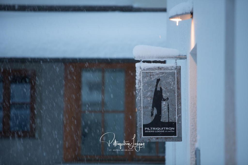 una señal colgando de una ventana con nieve. en Piltriquitron Lodging, en Sankt Anton am Arlberg