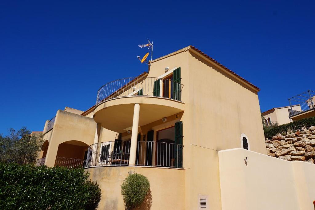 a white building with a balcony on top of it at M&M House in Cala Romàntica