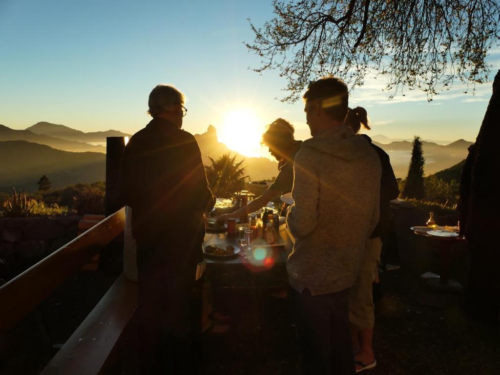 a group of people standing around a table at sunset at Mountain Hostel Finca La Isa in Tejeda