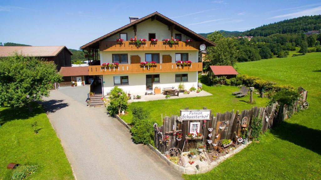 ein Haus mit Blumen auf den Balkonen auf einem Feld in der Unterkunft Pension Schuasterhof in Bodenmais