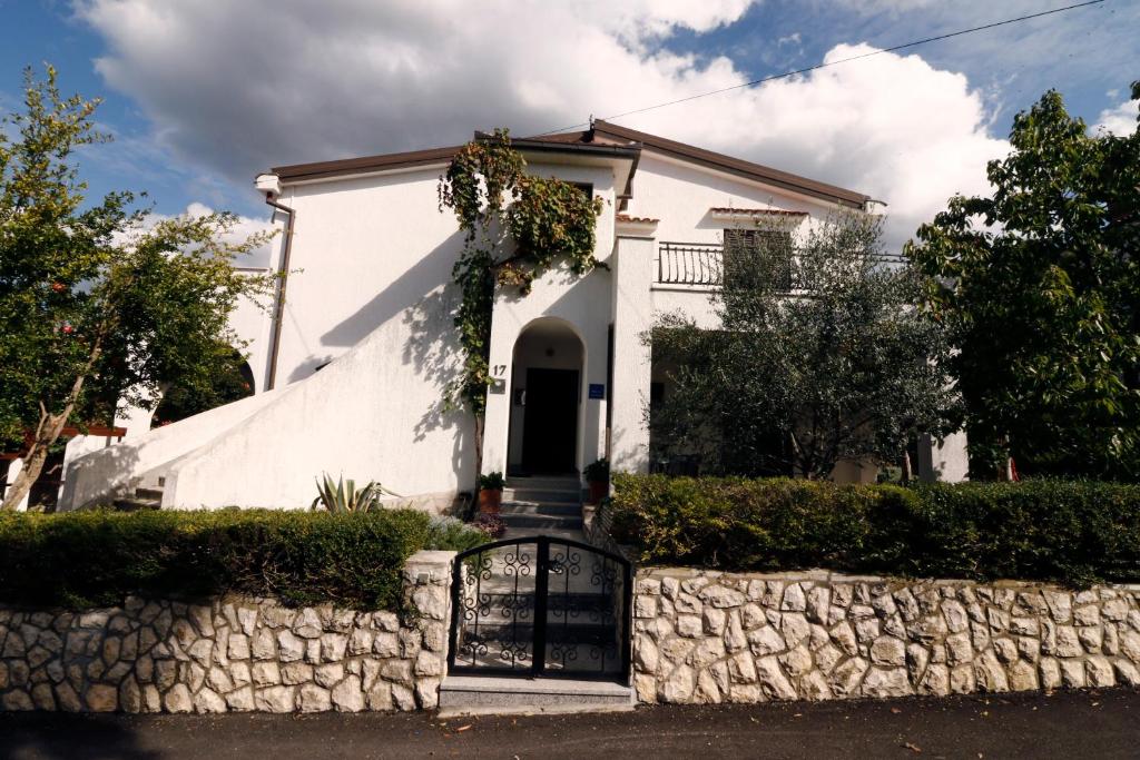 une maison blanche avec un portail et un mur en pierre dans l'établissement Apartment Draga 17, à Njivice