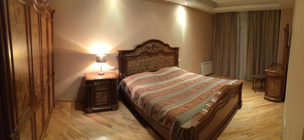 a bedroom with a bed and a lamp on a table at Bachos Apartment in Tbilisi City