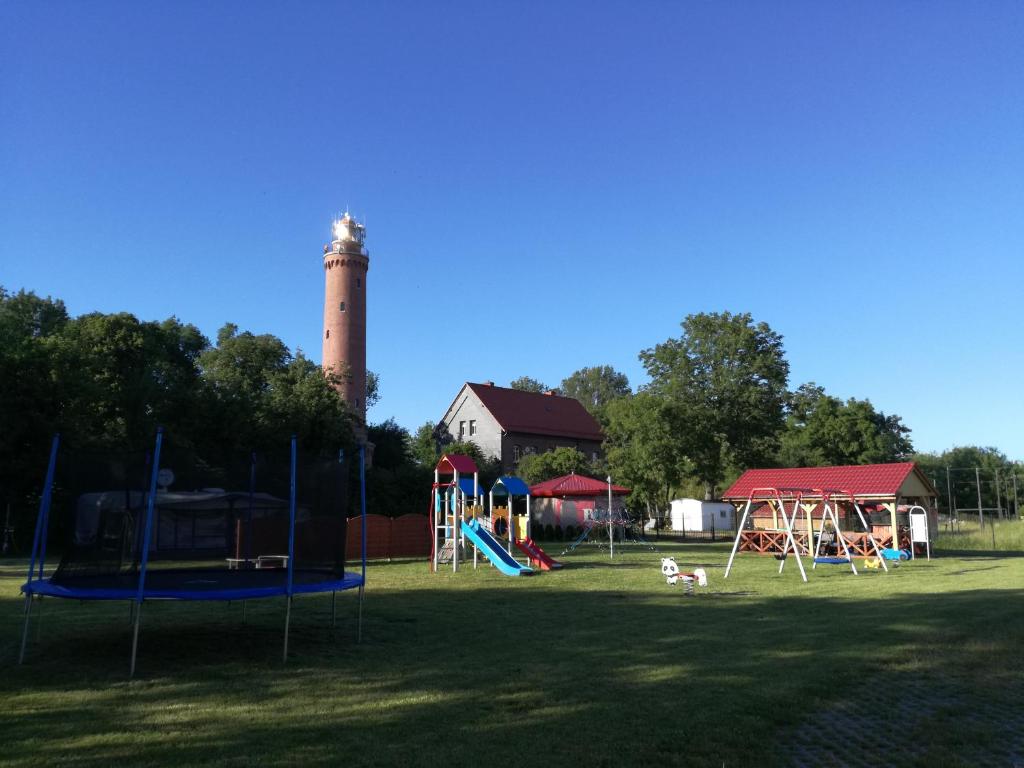 a park with playground equipment with a lighthouse in the background at Domki drewniane OW Latarnik in Gąski