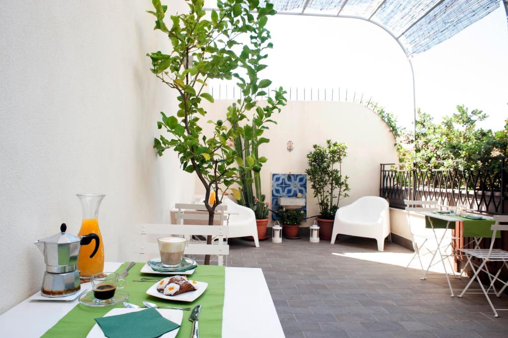 un patio con mesa, sillas y plantas en B&B Cannoli, en Palermo