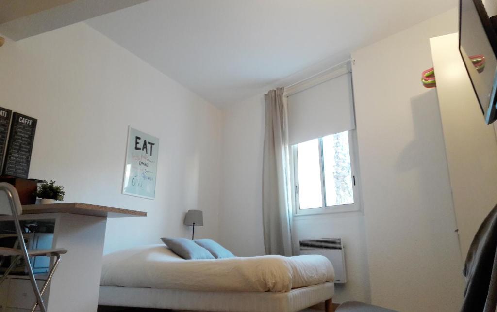 a white bedroom with a bed and a window at Studios Raphael in Saint-Raphaël