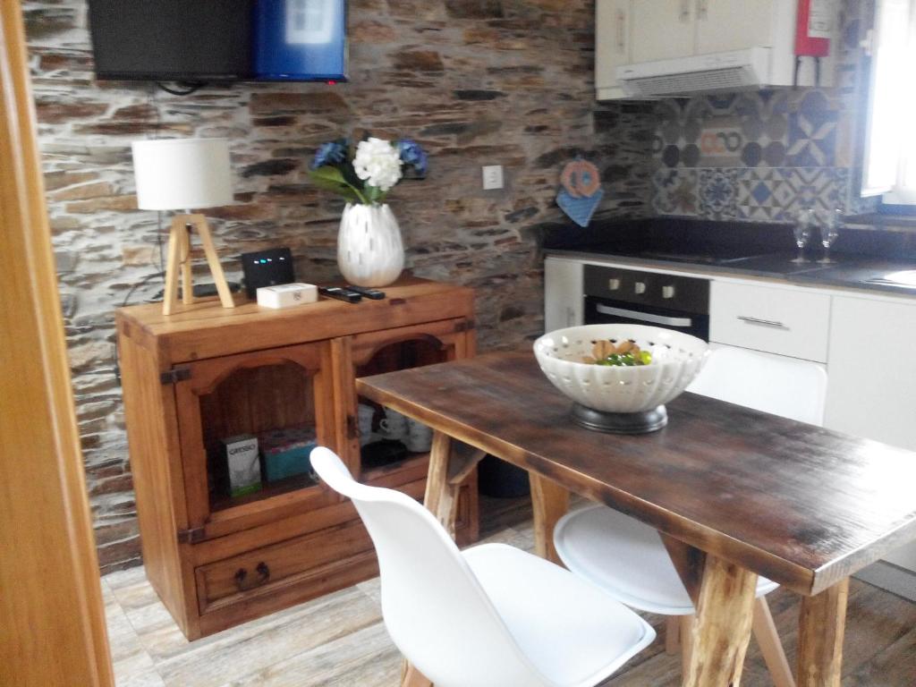 uma cozinha com uma mesa de madeira e cadeiras brancas em Casa da Alta em Coja
