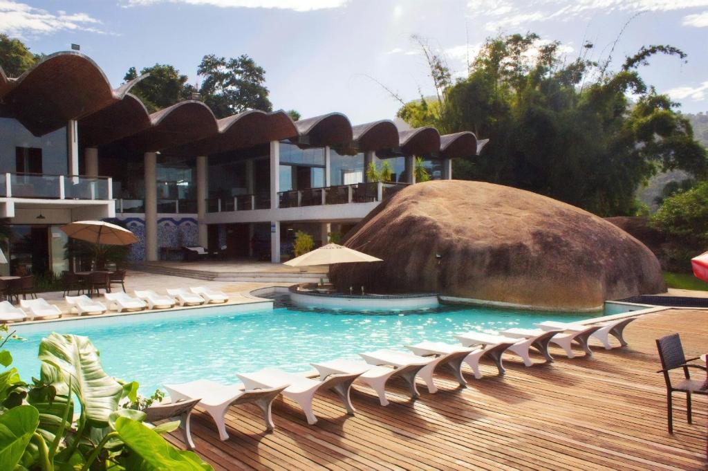 a pool with chairs and a large building at Flat no Portogalo in Angra dos Reis