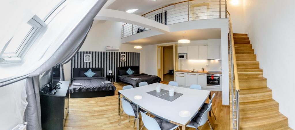 ein Wohnzimmer mit einem Tisch, einer Küche und einer Treppe in der Unterkunft Riverside SPIRIT in Prag
