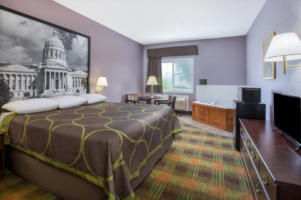 a hotel room with a large bed and a bathroom at Super 8 by Wyndham Sweet Springs in Sweet Springs