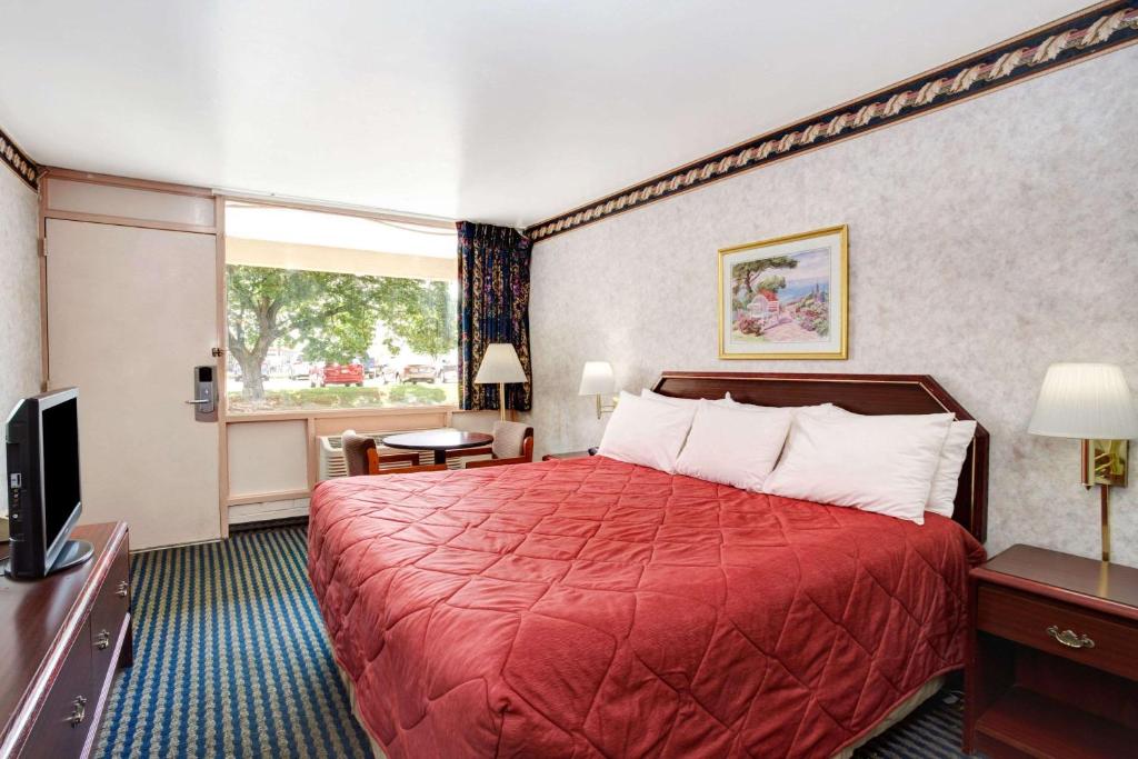 a hotel room with a red bed and a television at Ramada Limited Cockeysville in Cockeysville