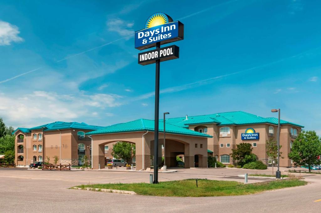 una señal para alds inn y suites en un estacionamiento en Days Inn & Suites by Wyndham Brandon en Brandon