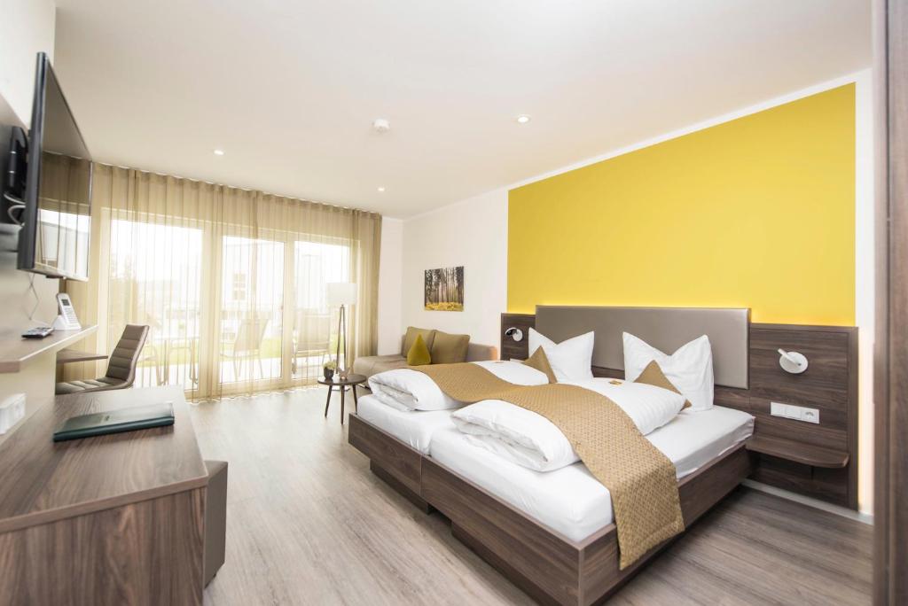een slaapkamer met een groot bed met een gele muur bij No. 12! Apartmenthaus in Bad Soden-Salmünster