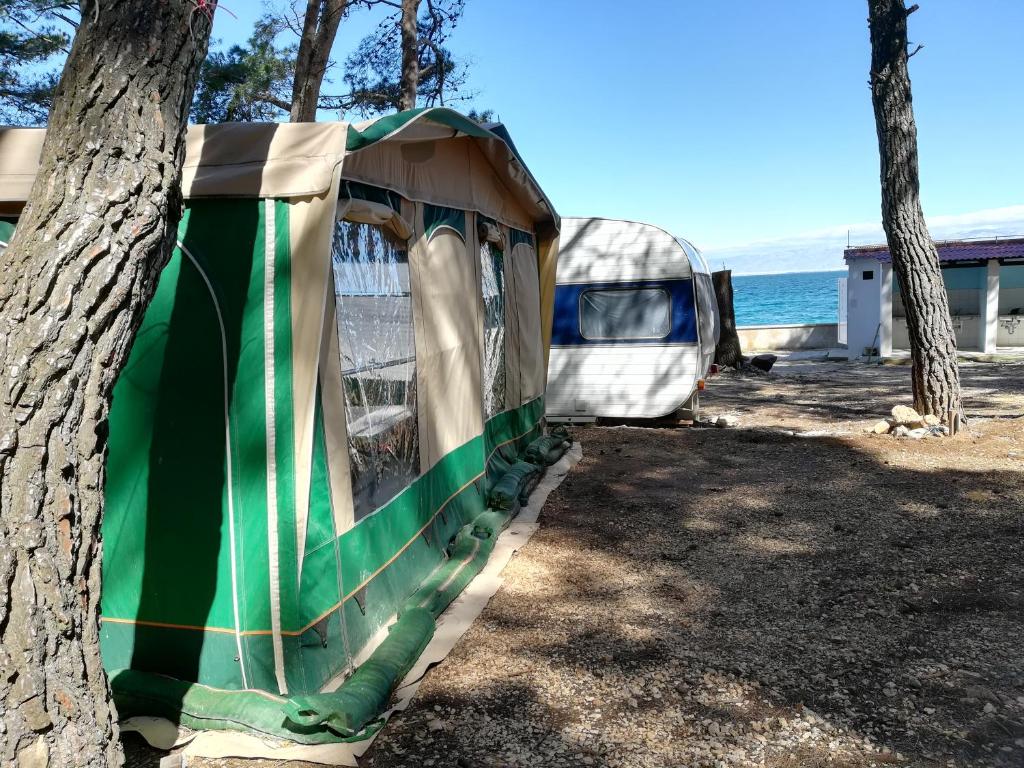 tenda verde e bianca seduta accanto a un albero di Caravan near the sea a Ugljan (Ugliano)
