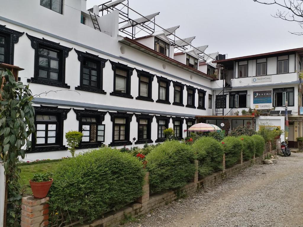 a large white building with black windows and bushes at Hotel Heranya in Kathmandu