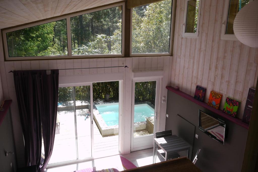 Elle offre une vue sur une maison dotée d'une piscine et de fenêtres. dans l'établissement Un Matin D’été, à Lacanau-Océan