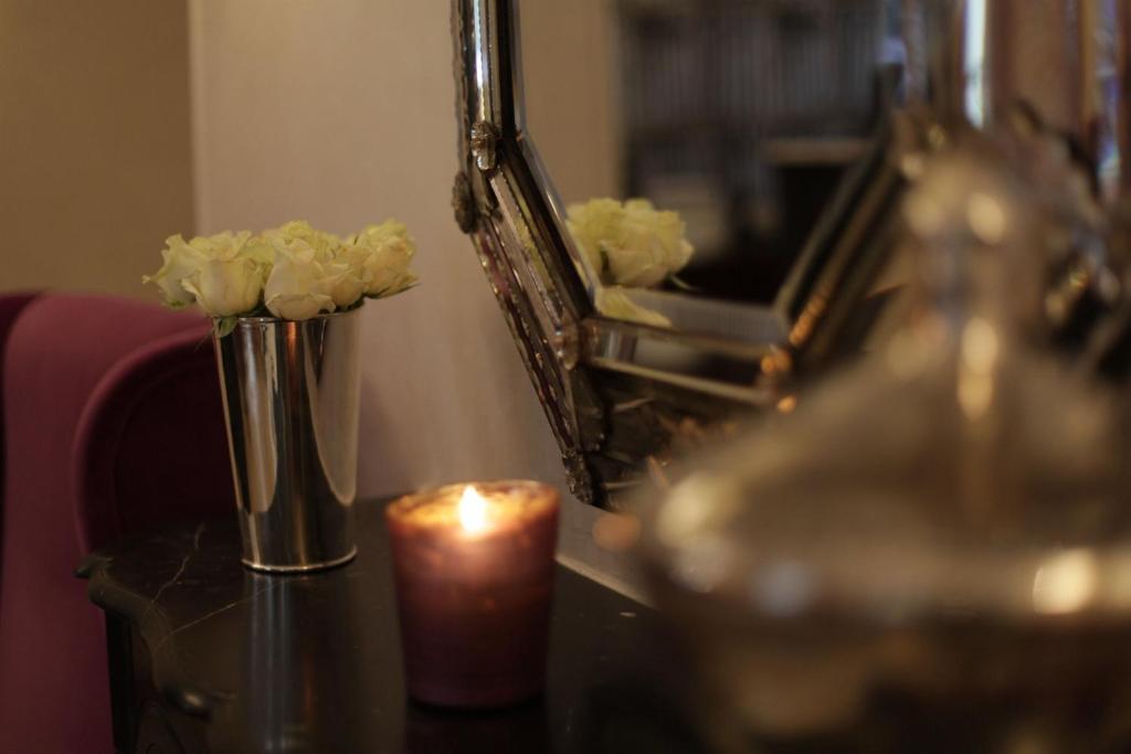 a candle and flowers on a table in front of a mirror at Magda Champs Elysées in Paris