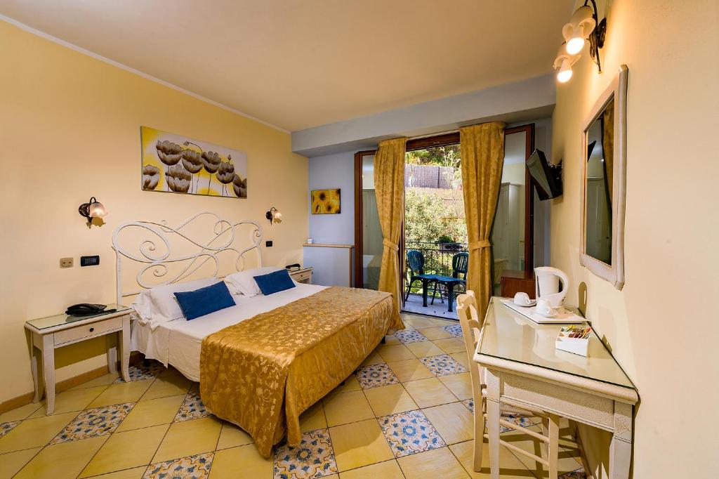 a bedroom with a bed, a desk, and a lamp at Hotel Cala Marina in Castellammare del Golfo