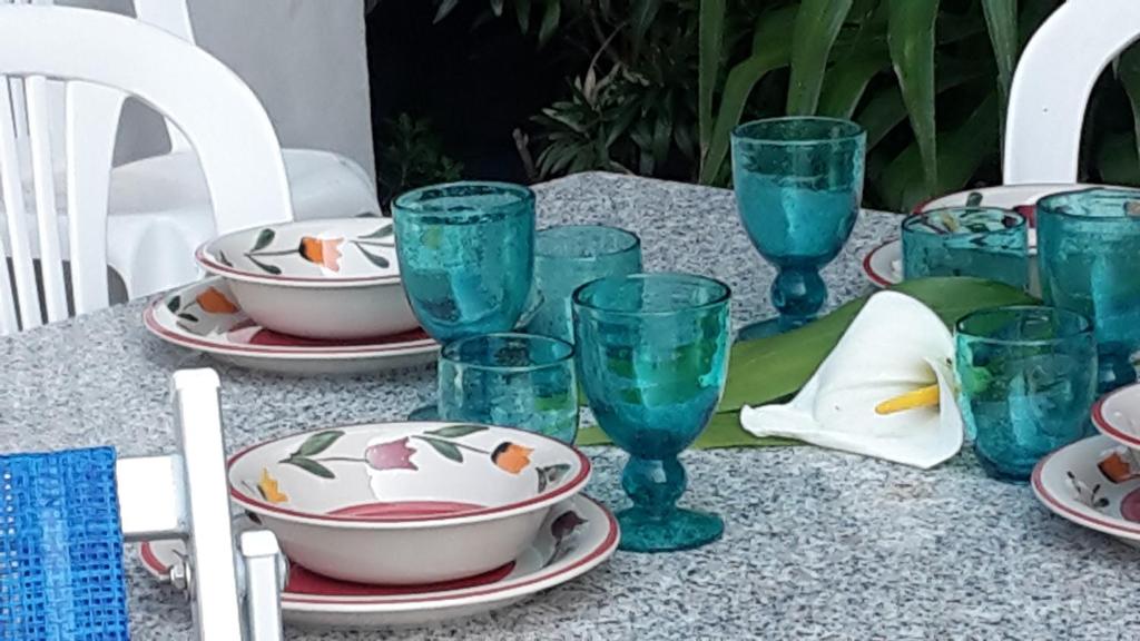 une table avec des verres bleus et des assiettes dessus dans l'établissement Alassio Mare e non Solo, à Alassio