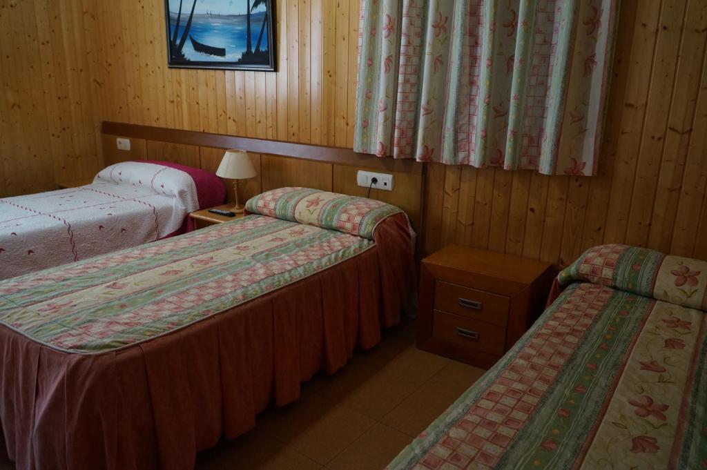 Habitación con 2 camas y mesa con lámpara. en Hostal Camino Real, en Calzadilla de la Cueza