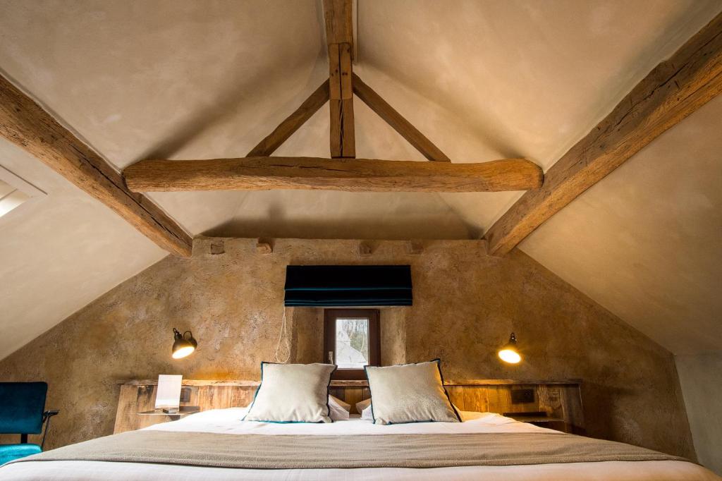 a bedroom with a large bed with wooden beams at Hotel Victoria - Maison Caerdinael in Durbuy